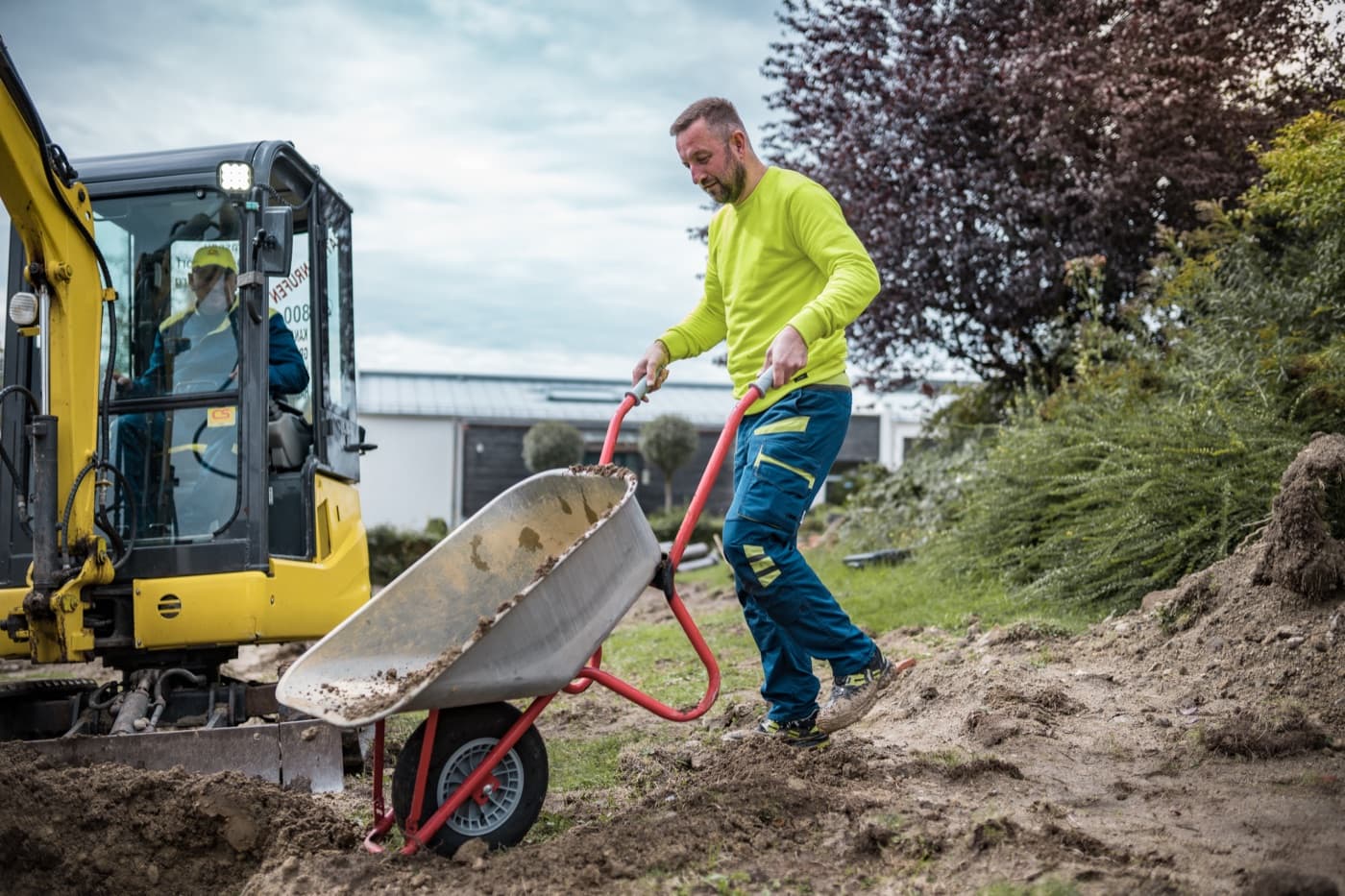 Monteur der Kanalservice CS GmbH mit Schubkarre an einem offenen Leitungsgraben